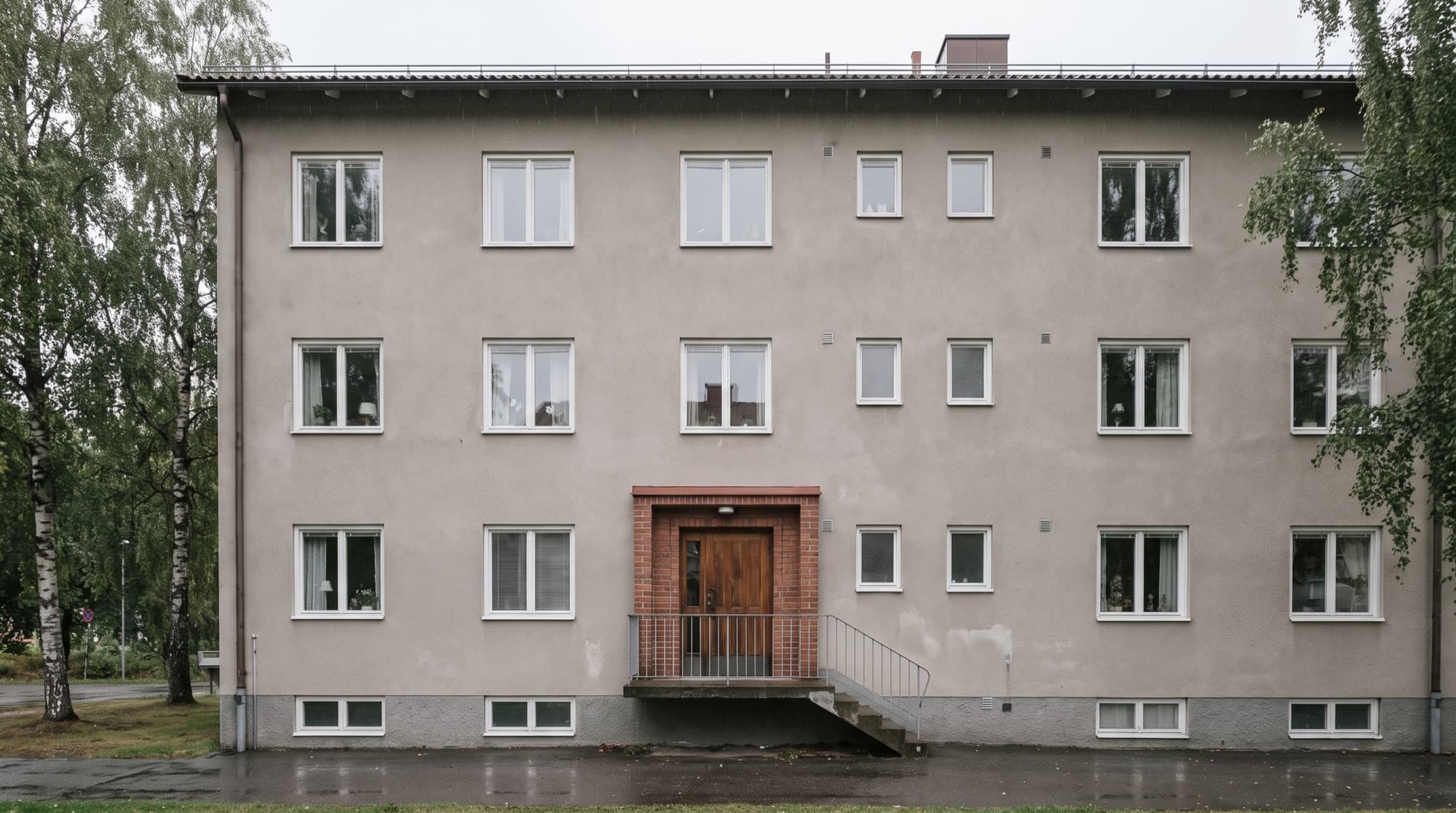 Flerbostadshus från 1960-talet med tegelinramad entré och trappa